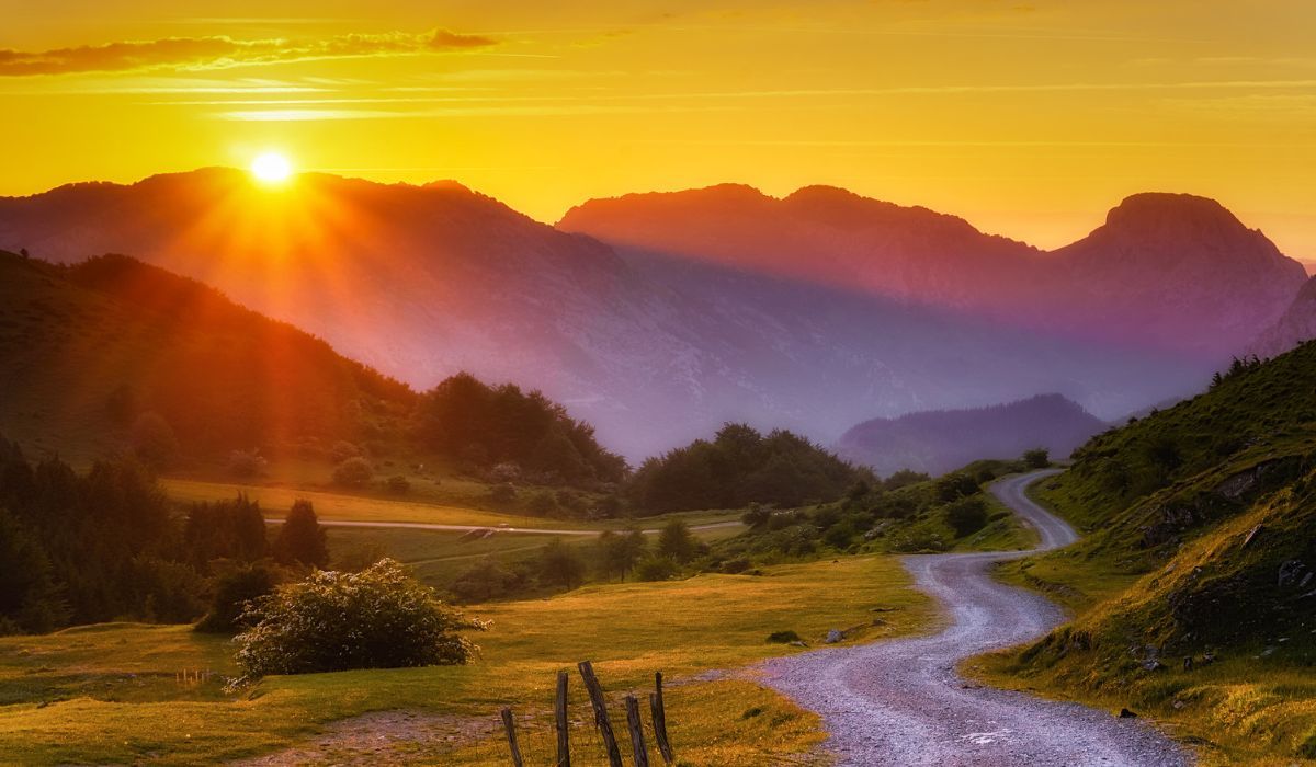 sentiero in salita che conduce alla cima di una montagna illuminata dal Sole